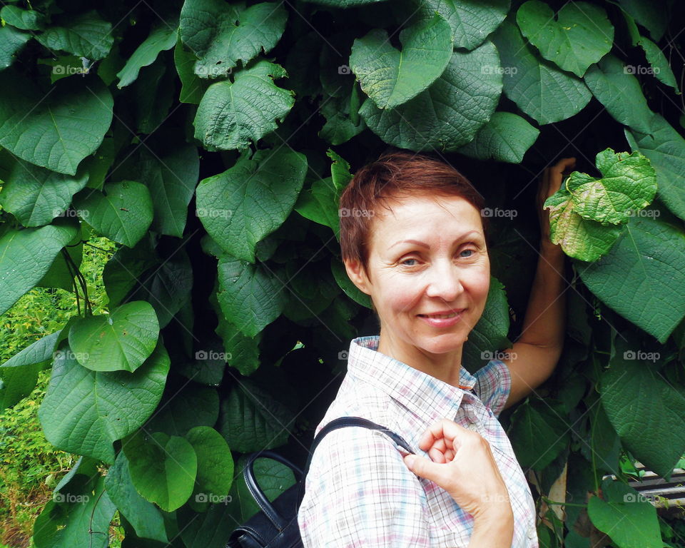 girl on the background of a bush with green leaves