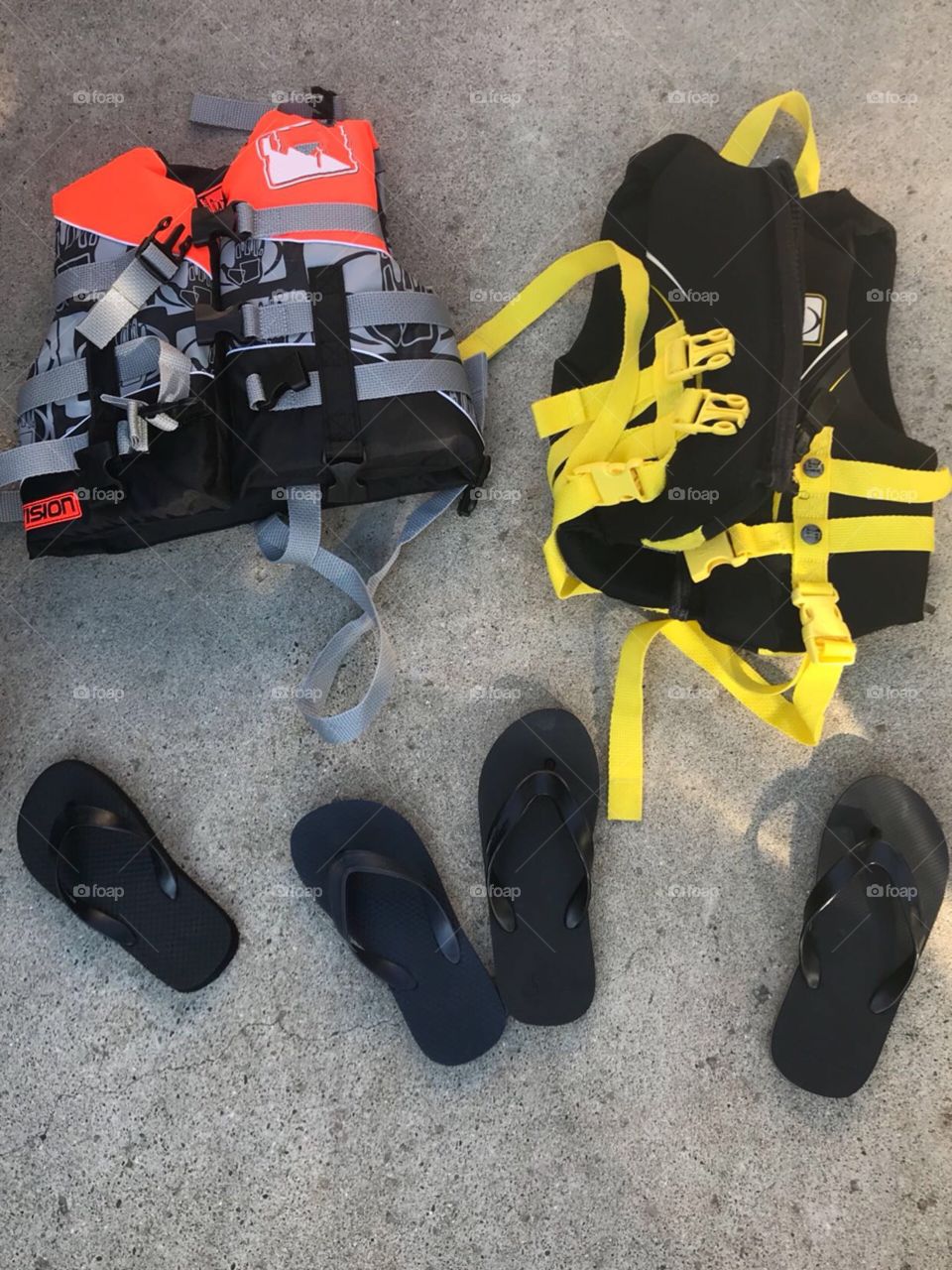 Brightly colored Life jackets and flip flops getting ready to go to the beach on a hot summers day 