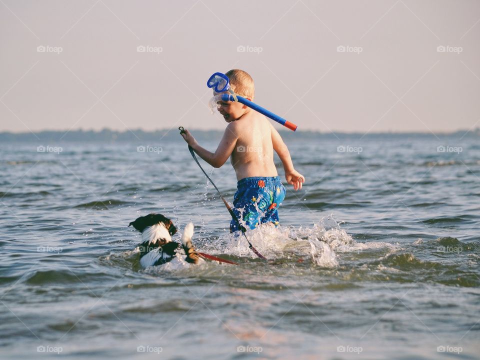 Boy playing with a dog at ocean