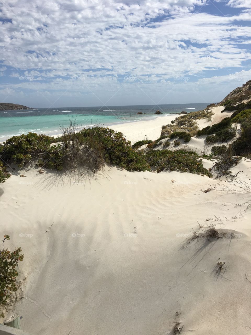 Sand dunes surrounding a secluded remote pristine white sand beach in south Australia's showing the shoreline and turquoise blue sea in a national park near coffin bay