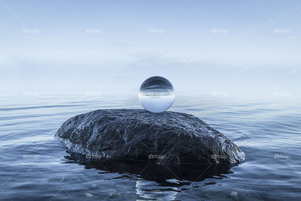 Crystal orb on a rock in the ocean