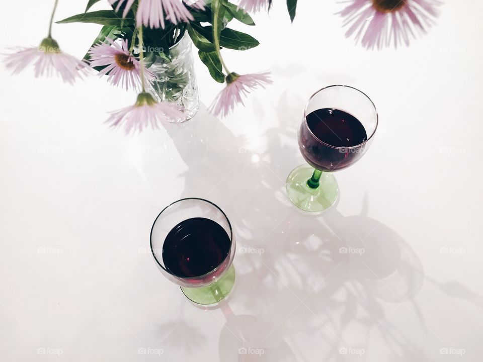 Two glasses with red wine and vase of flowers in harmony in color