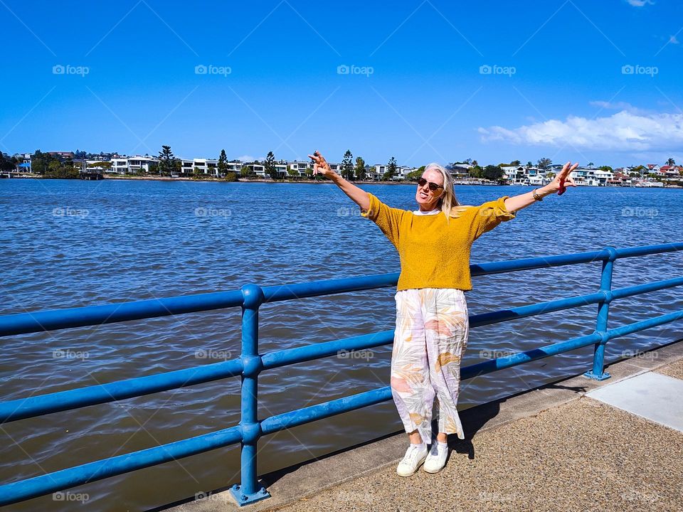 Blonde woman walking happy by the Brisbane river in sunny Australia.