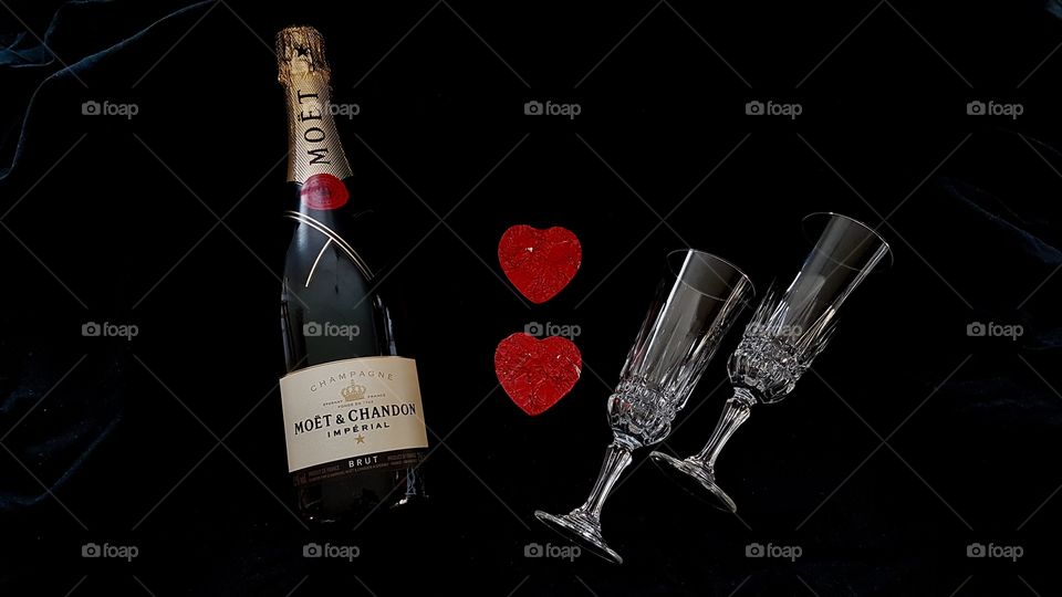 Romance, a bottle of champagne and two hearts and crystal glasses on black background - Romantik, en flaska champagne, två hjärtan och glas 