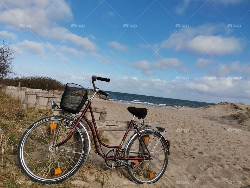 Isolated bicycle at the beach with a blue sky and some white clouds