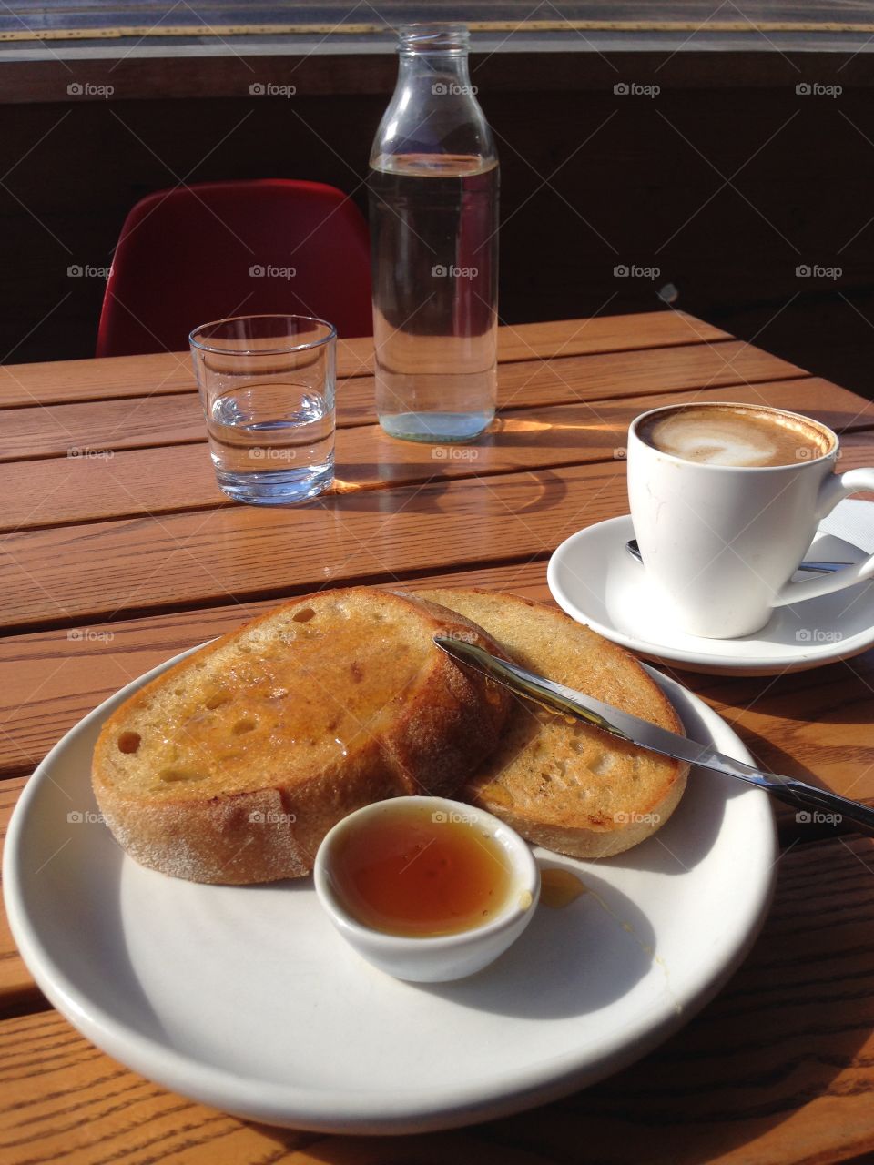 Cafe breakfast, cafe, outside, street , street eats, coffee, cup,  toast and honey, wooden table, glasses, water, bottle 