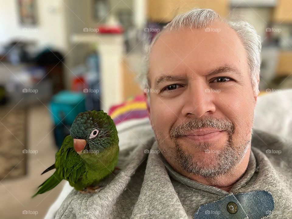 Tender moment between man and parrot.