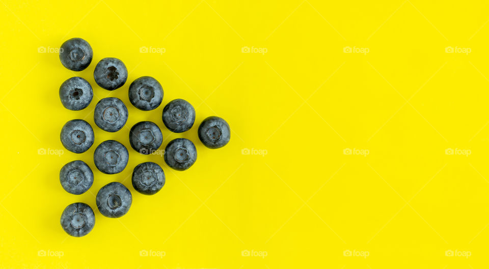 Fresh organic blueberries on yellow background with copy space, flatlay