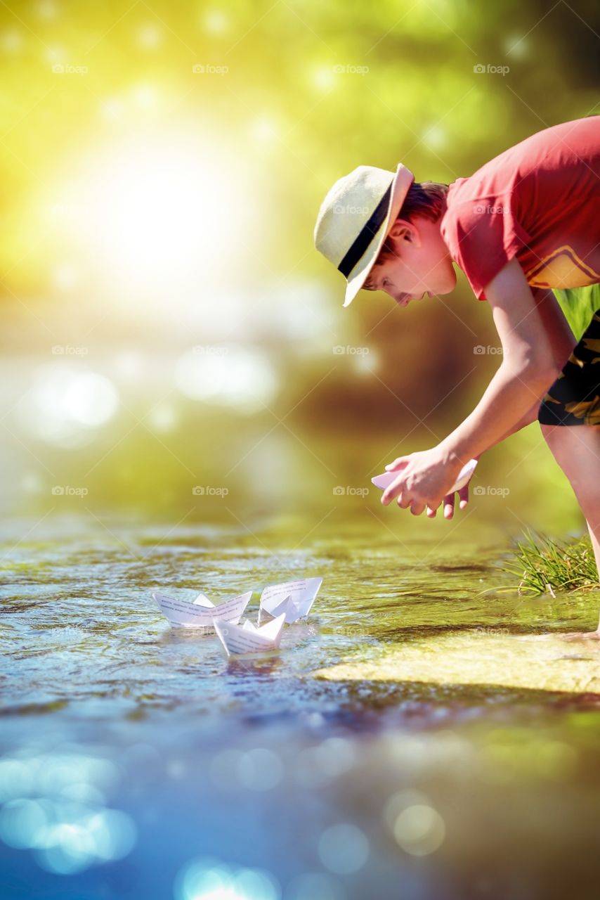The boy launches paper boats in the river for rest in the countryside in the village.
