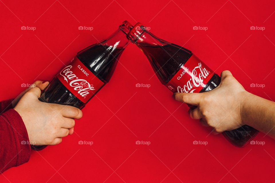 childrens hands hold bottles of coca cola