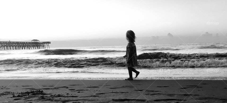 Small child walking on the beach looking out over the ocean
