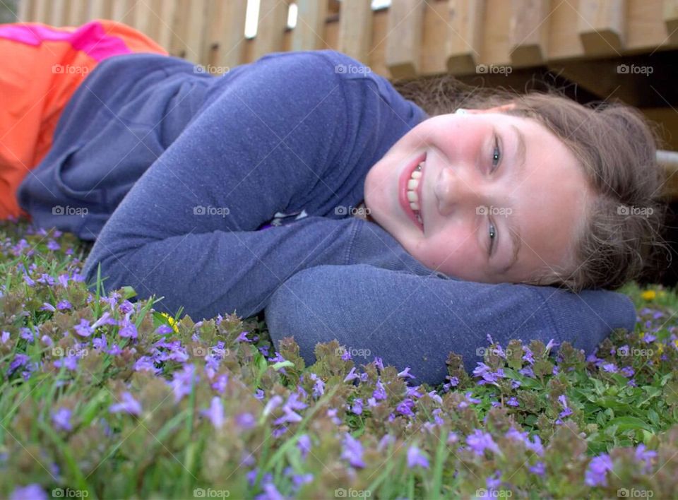 My beautiful nine-year-old daughter laying in a patch of pretty, purple flowers. 