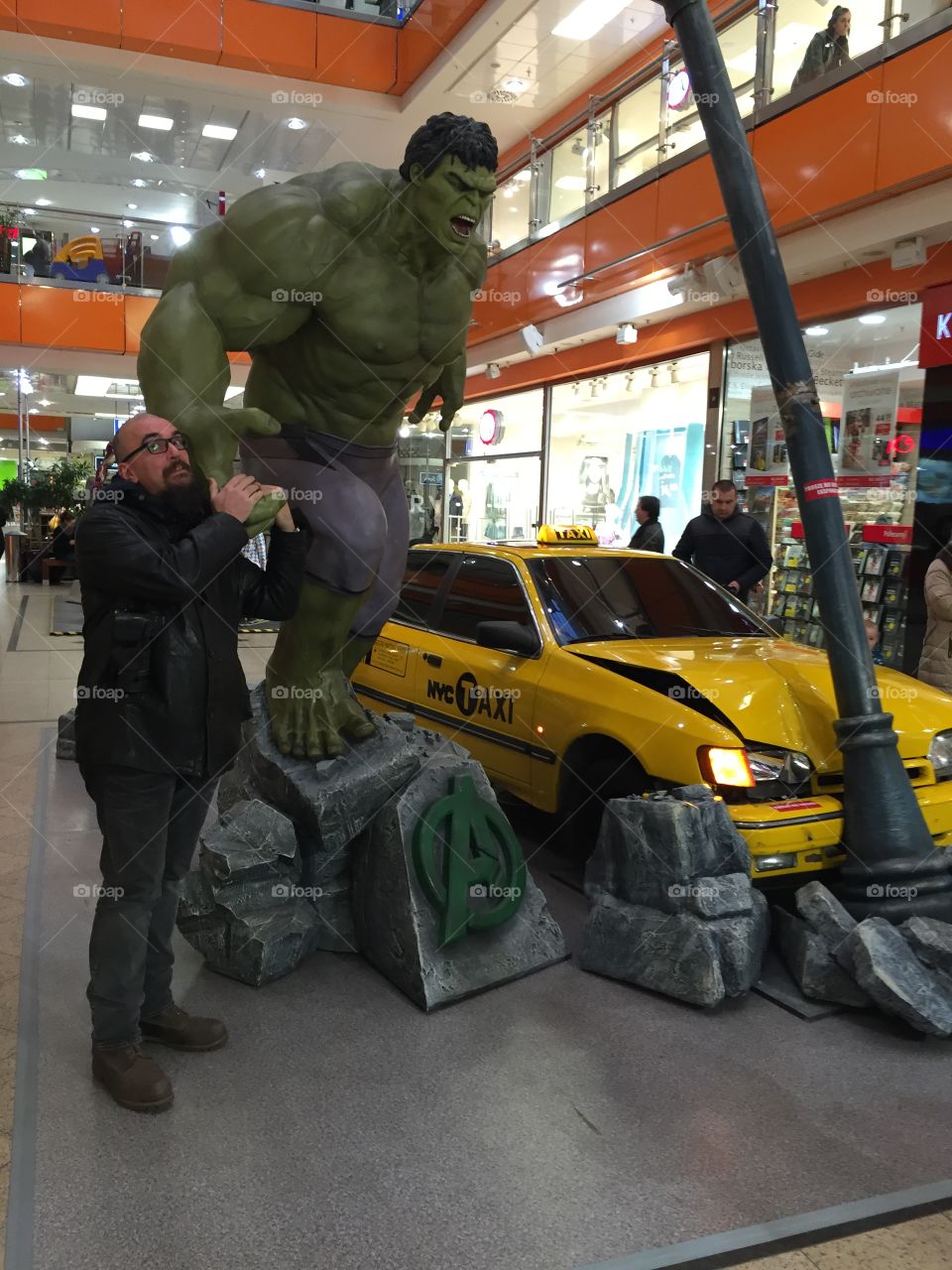 Mature man standing near avenger statue in shopping mall