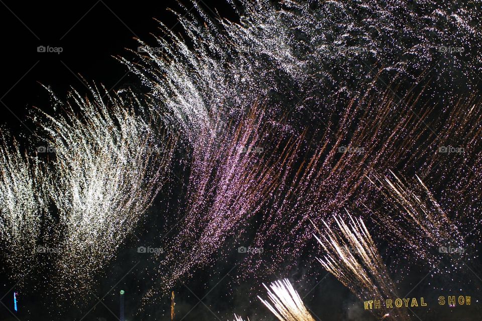 Flashy streaks of fire across the smoky night sky bursting upwards with poppy sounds at the Perth royal show
