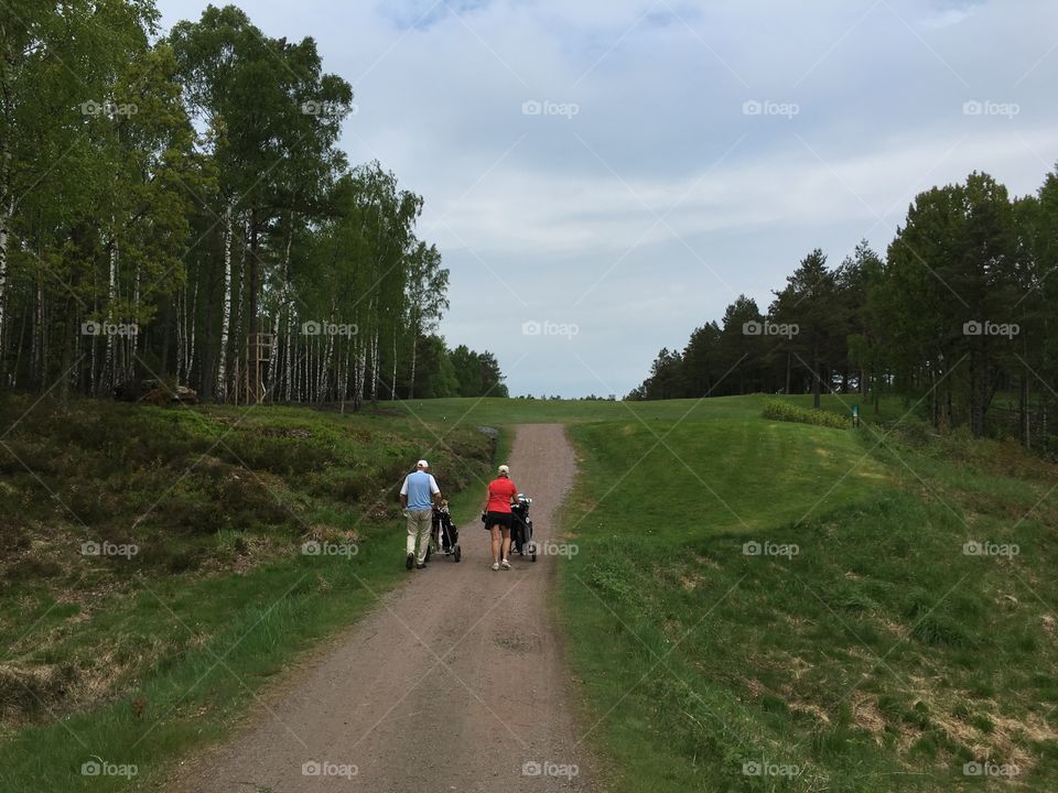 Two elderly golfers walking between golf holes