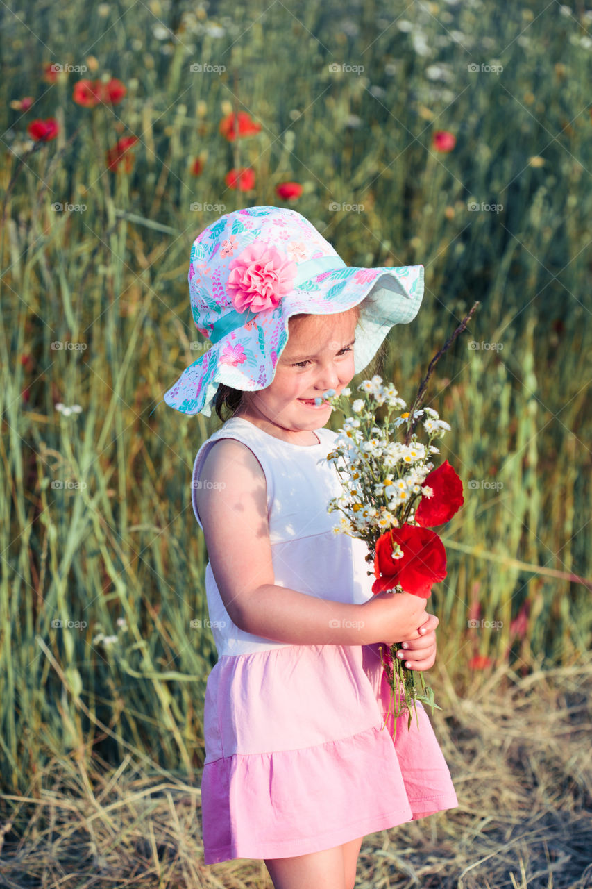 Lovely little girl in the field of wild flowers. Cute girl picking the spring flowers for her mom for Mother's Day in the meadow. Spending time close to nature