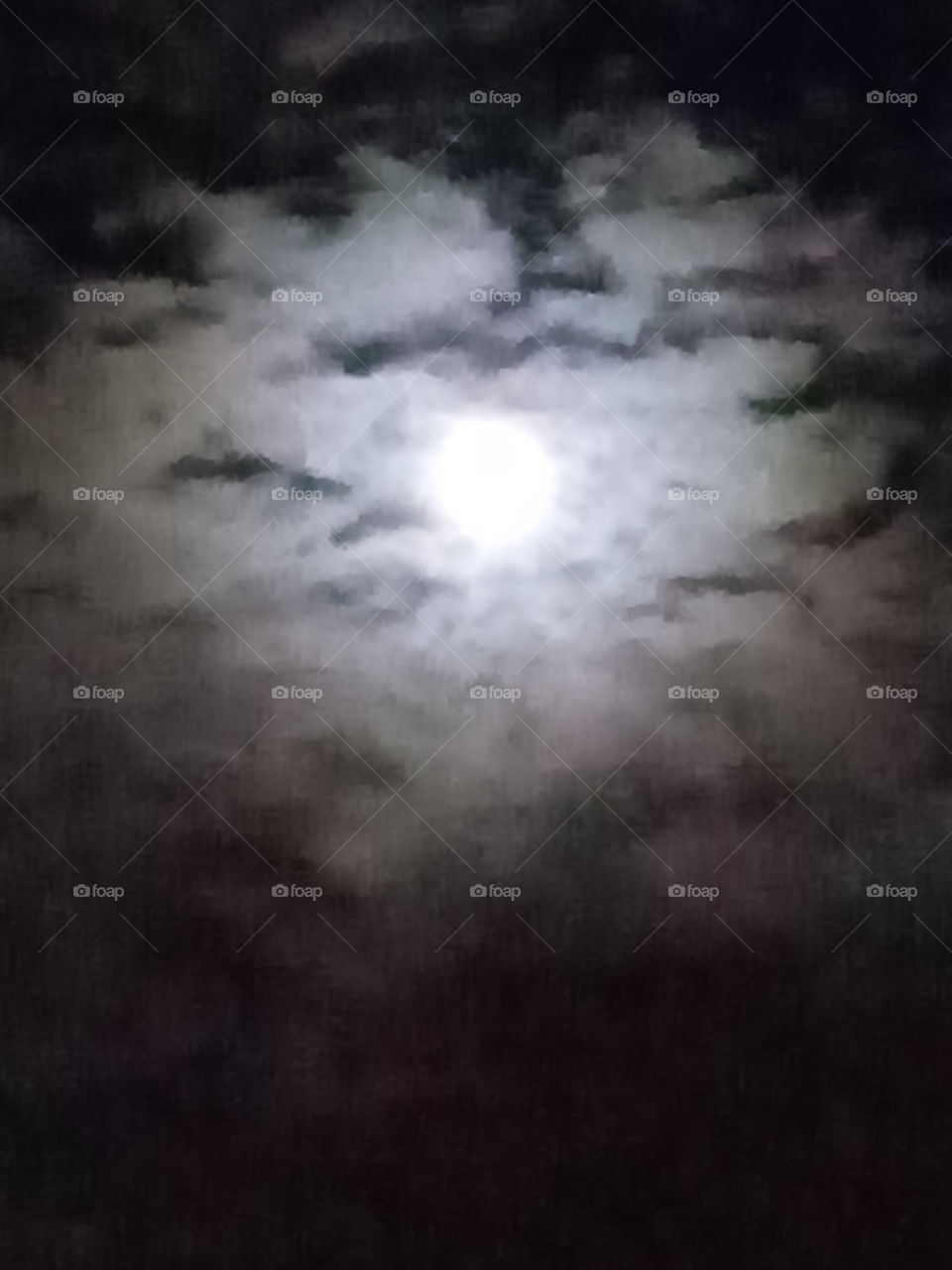 The moon from afar surrounded by clouds